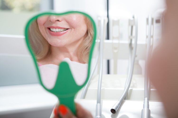 Paciente revisando su sonrisa frente al espejo tras consulta con dentista en A Coruña